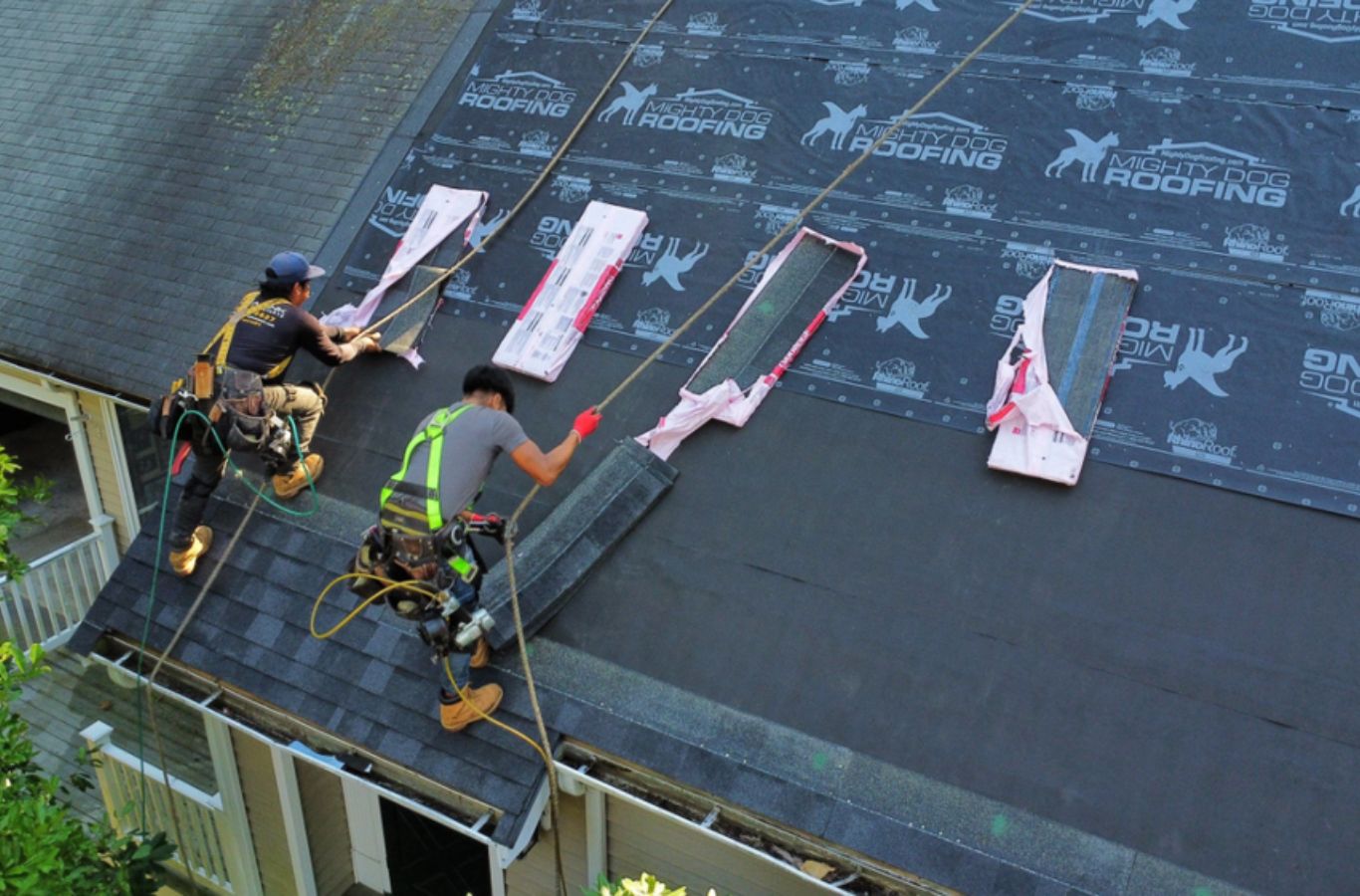 Un técnico de Mighty Dog Roofing of Greater Middlesex County realizando servicios profesionales de techado en Westford, MA con herramientas de calidad.